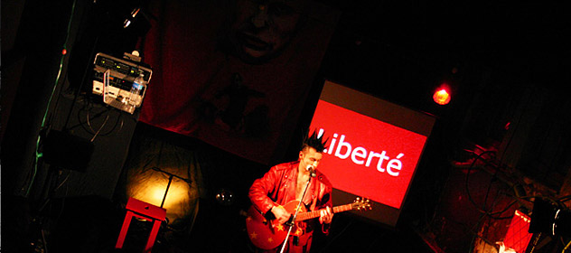 Photo de Vaquette, squat de la Miroiterie, avec une guitare devant le mot liberté